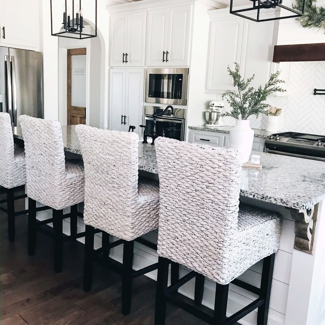 Wicker barstools pulled up to a farmhouse style marble bar.