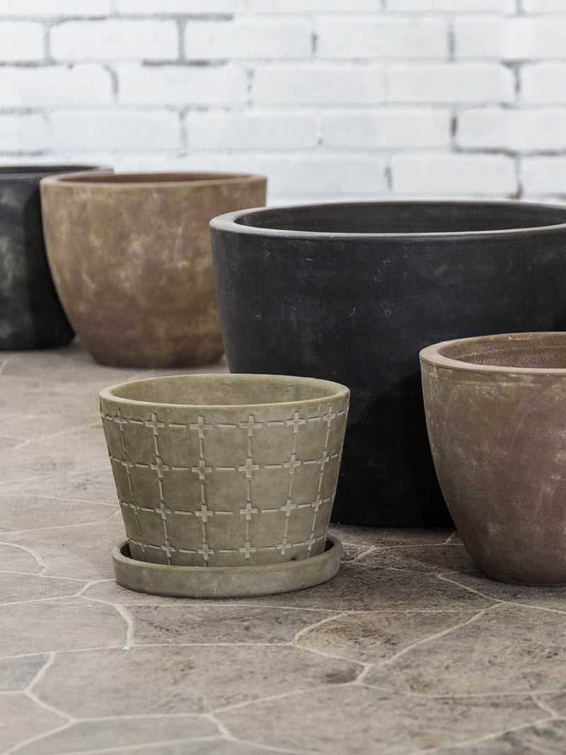 An assortment of cement planters in different sizes and colors sit on a tile floor